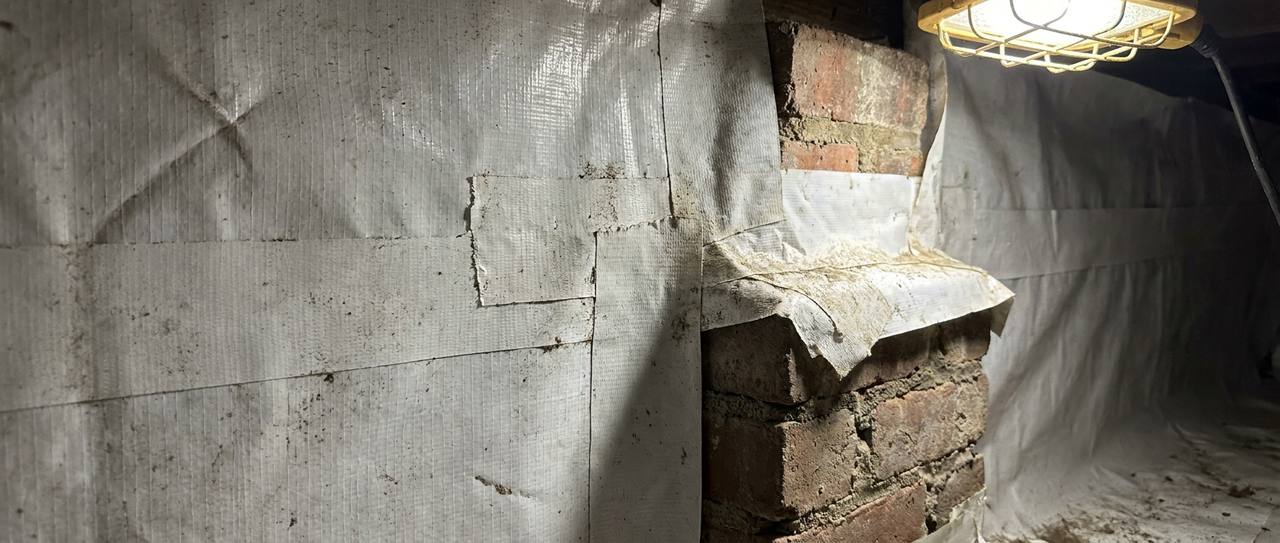 Close-up of sealed and taped vapor barrier seams around a crawl space support pier